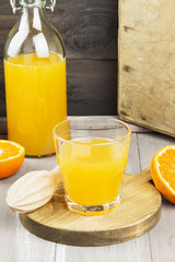 Tangerine juice in glass and fresh fruit on a wooden background