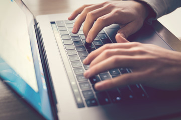 Man's hands typing on laptop keyboard