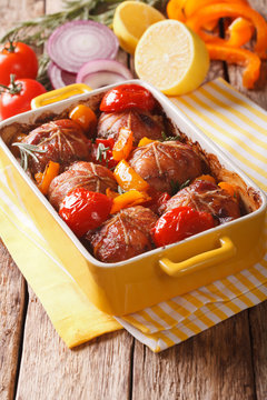 Ballotine rabbit baked with tomatoes, pepper and rosemary close up in baking dish. vertical