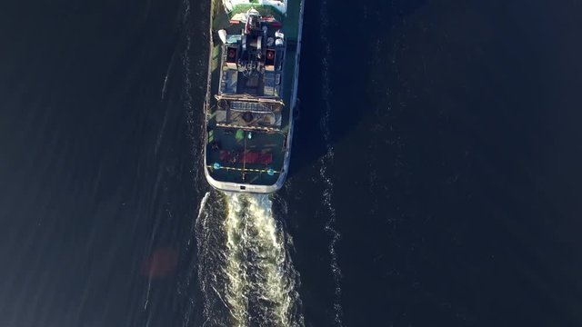 Tug pushing a barge on the river. The camera moves in the sky over the ship, looking straight down. Transportation on the river. Aerial view.