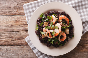Paella from black rice with seafood close-up on a plate. horizontal top view