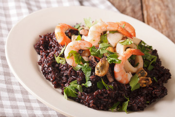 Paella from black rice with seafood close-up on a plate. horizontal