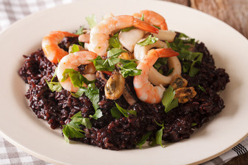 Risotto of black rice with seafood close up on a plate. horizontal