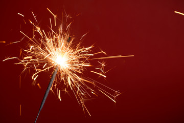 Flaming sparkler on red background