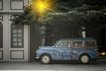 Detail of Blue retro car and green tree background with lighting flare effect. Vintage style