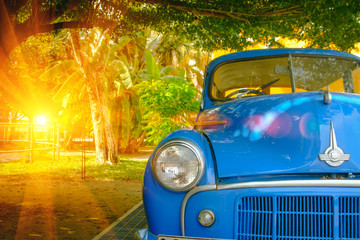 Detail of front view blue retro car with lighting flare effect. Vintage style