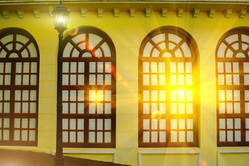 Classice wood window on yellow wall background with lighting flare effect on window.