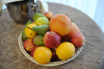 A basket of fruit on a table by the window.