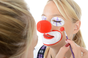 Visagist oder Maskenbildner schminkt Frau zum Clown 
