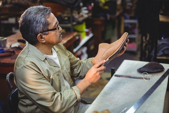Shoemaker examining a shoe - Powered by Adobe
