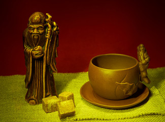 Still life with a statuette of the god of tea, a cup and lumps o