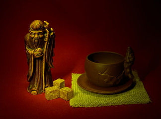 Still life with a statuette of the god of tea, a cup and lumps o