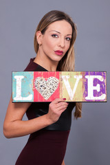 Woman wearing red dress holding sign love symbol