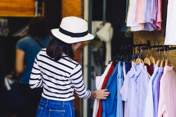shopping, fashion, style and people concept - happy asian woman choosing clothes
