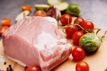 Raw pork on cutting board and vegetables 