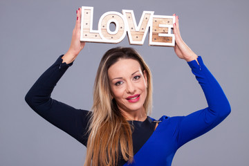 Woman wearing blue dress holding sign love symbol