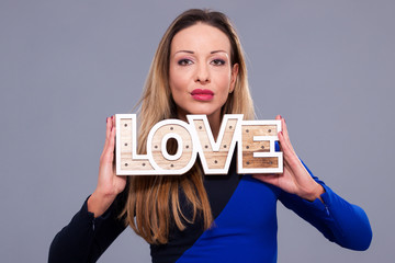 Woman wearing blue dress holding sign love symbol