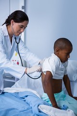 Doctor examining patient with stethoscope in ward