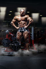 Fototapeta na wymiar very power athletic guy standing with barbell, workout in the gym