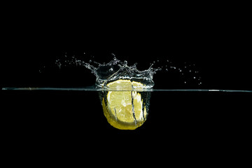 Zitronenscheibe taucht mit Spritzer in Wasser ein