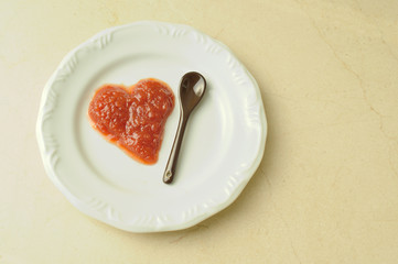 Plate with heart shaped portion of jam on a marble surface