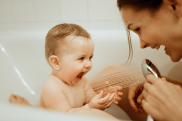 Mother washing shower happy newborn baby in bath - obrazy, fototapety, plakaty