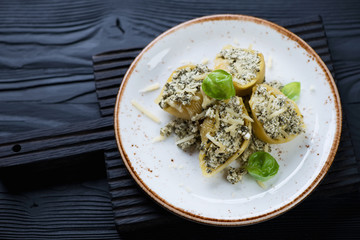 Conchiglioni with spinach and cheese over black wooden surface