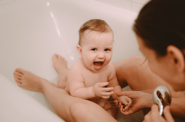 Mother washing shower happy newborn baby in bath