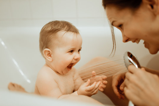 Mother washing shower happy newborn baby in bath