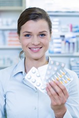 Smiling pharmacist showing medicine in pharmacy