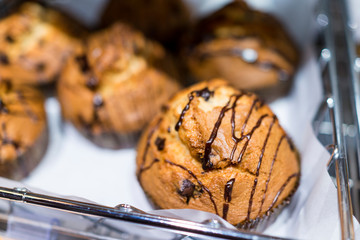 Chocolate drizzled chocolate chip muffins on tray display in bak