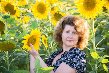 adult curly-haired woman in field of sunflowers