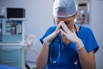Sad female nurse sitting in operation theater