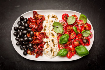 Italian appetizers - mozzarella, tomatoes, olives and basil