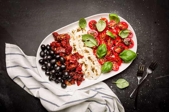Italian appetizers - mozzarella, tomatoes, olives and basil