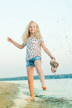 girl running on the beach at the water barefoot