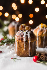 dolce tradizionale italiano di Natale. Piccolo panettone monoporzione con marron glacè e confetti dorati. Decorazioni e luci natalizie con effetto bokeh