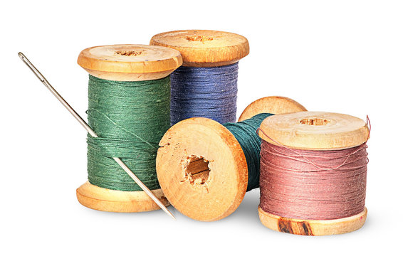 Needle and multicolored thread on wooden spool