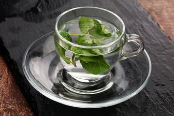 Cup of tea and mint leaf on a wooden background - hot water in a tearoom place