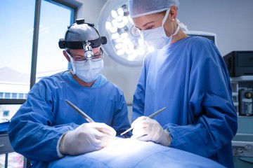 Surgeons performing operation in operation theater - obrazy, fototapety, plakaty