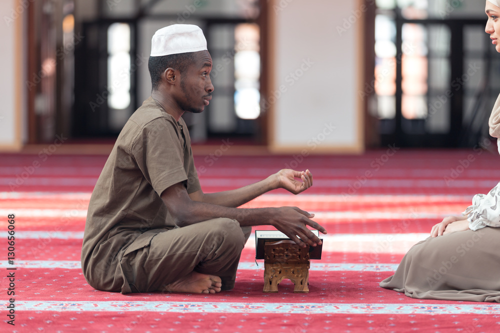 Wall mural Black Muslim man and woman praying in mosque