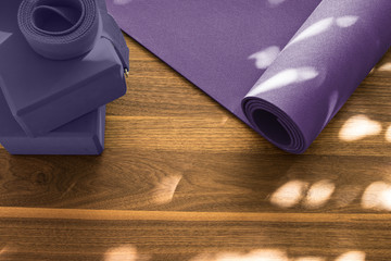 Yoga mat on wooden floor in evening light with shadows from wind
