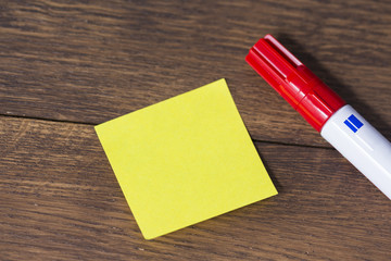 Yellow post-it with pen on office wooden table.