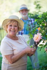 Senior woman cutting flower with pruning shears