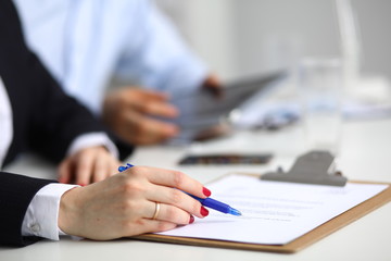 Businesswoman sitting in office, writing on documents