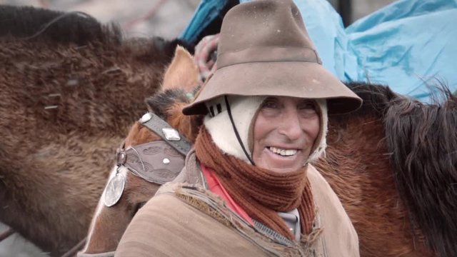 Native quechua man using a chullo and a highlander hat near his horse on the Andean mountains of Peru. Slow motion