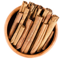 Cinnamon sticks in wooden bowl. Raw brown quills from inner bark of Cinnamomum. Cassia, aromatic spice used as condiment and for flavoring. Isolated macro food photo close up from above over white.