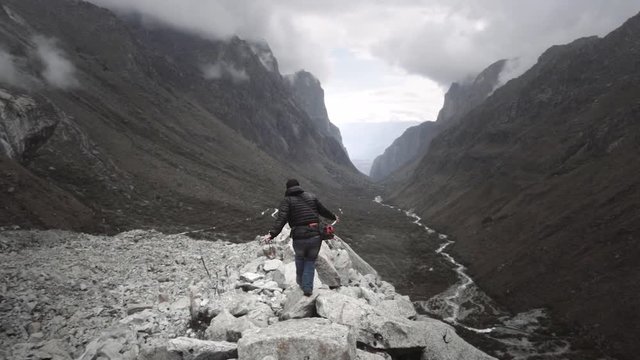 Man jumps on the rocks of a panoramic view on Huascaran Natural Park to escape of the storm. Slow motion