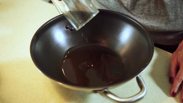 Cooking curd casseroles. Female hands pouring the sunflower oil and honey to the frying pan.