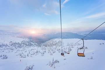 Ski lift with seats going over the mountain and paths from skies - obrazy, fototapety, plakaty